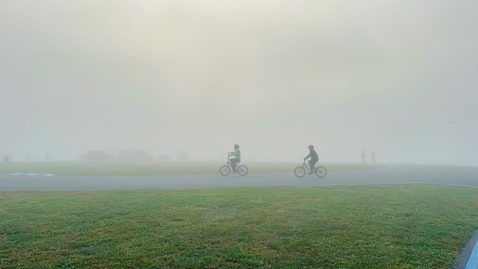 Two riders crossing the field in heavy morning fog